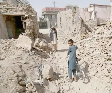  ??  ?? Afghan residents walk near destroyed houses after a Taliban attack in Ghazni. — AFP photo