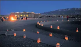  ??  ?? A bonfire keeps visitors warm and luminarias line the trails around Coronado State Monument near Bernalillo during a Christmas celebratio­n.