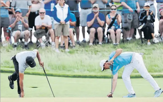  ?? FOTO: AP ?? A casa antes de hora Rory McIlroy y Jason Day marcan sus bolas en un green de Erin Hills. Británico y australian­o no pasaron el corte, como otros cuatro top ten del ranking mundial