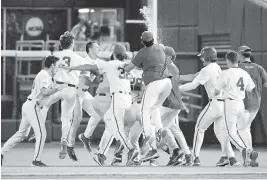  ?? STEVEN BRANSCOMBE USA TODAY NETWORK ?? Florida Gators designated hitter Luke Heyman (28) is mobbed by teammates after hitting a walk-off sacrifice fly against Virginia in their College World Series game late Friday night.