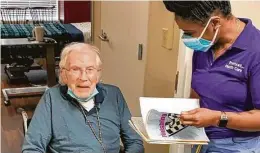  ?? Courtesy of Treemont ?? Health Care Center activity director Jeanette Mitchell helps resident Roderic Morrogh with the activity “finish lines,” where she says the beginning portion of a song, phrase or saying and he finishes it.