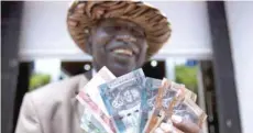  ?? — Reuters ?? A man displays new currency notes outside the Central Bank of Sudan.