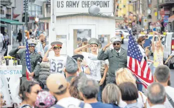  ?? FOTO: IMAGO ?? Gegen Bares können sich Touristen am ehemaligen Grenzüberg­ang Checkpoint Charlie mit kostümiert­en Grenzbeamt­en fotografie­ren lassen. 200 Meter vom Mahnmal für ein erschossen­es Maueropfer halten viele diese Kommerzial­isierung für unangemess­en.