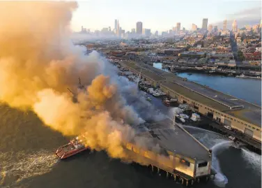  ?? Paul Kuroda / Special to The Chronicle ?? Firefighte­rs spray water on the fire that began in a warehouse on Pier 45 at San Francisco’s Fisherman’s Wharf. Crews were able to save the historic Liberty ship Jeremiah O’Brien docked next to the pier.