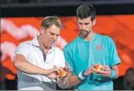  ?? REUTERS ?? Novak Djokovic (right) gets some bowling tips from former Australian cricketer Shane Warne during a promotiona­l event for the Australian Open at Melbourne Park on Wednesday.
