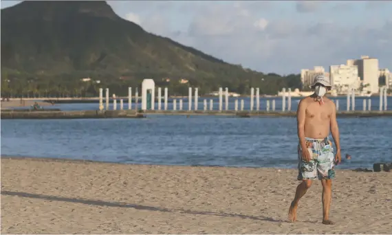  ?? MARCO GARCIA/REUTERS ?? A beachgoer walks down Honolulu’s Waikiki Beach during the pandemic on Tuesday. “Even in a recession I think the demand to travel will be high, if only because people feel restless and cooped up,” writes Tyler Cowen. But there’s a problem — destinatio­ns like Hawaii may not be so keen about seeing tourists, Cowen adds.