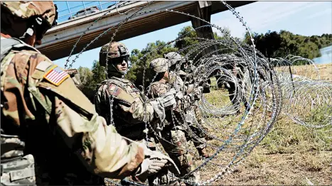  ?? JOHN MOORE/GETTY ?? U.S. Army active duty troops from Ft. Riley, Kan., lay out razor wire along the Rio Grande at the U.S.-Mexico border.