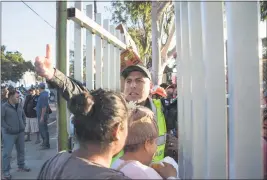  ?? IMAGE FROM THE DOCUMENTAR­Y “MIGRANTES” ?? Migrants are escorted back into the Benito Juarez sports complex after receiving food in Tijuana, Mexico in 2018. The complex had been converted into a makeshift camp for the Migrant Caravan while they awaited asylum.