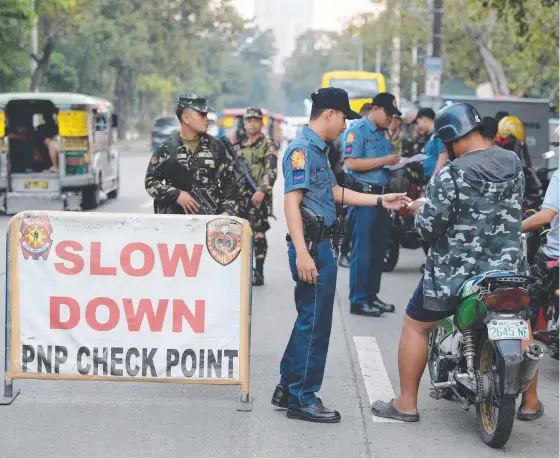  ?? ON ALERT: Philippine soldiers and policemen man a checkpoint in Manila as the country ramps up its fight against the IS terror threat in the country. ??