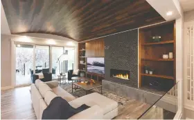  ??  ?? The striking great room features a linear gas fireplace flanked by built-in walnut cabinets. The eye-catching 10-foot barrel ceiling is made from luxury vinyl plank.