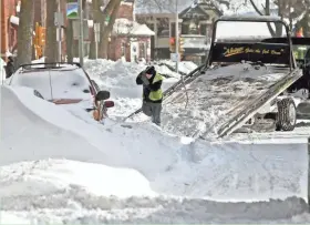  ?? SENTINEL BENNY SIEU/MILWAUKEE JOURNAL ?? A car is being towed, as soon as it can be dug out of a snowdrift, on Milwaukee’s east side on Feb. 2, 2011. City crews began towing cars left under mountains of snow in a bid to clear the streets.