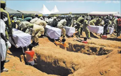  ?? Andrew Kasuku ?? The Associated Press Coffins of some of the victims of the MV Nyerere passenger ferry’s sinking are laid into graves during a mass burial ceremony Sunday on Ukara island, Tanzania.