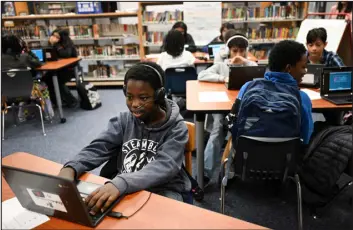  ?? HELEN H. RICHARDSON — THE DENVER POST ?? Allakassou­me Diallo, 12, studies on his computer in a math interventi­on class that is meeting in the library because the school is running out of rooms for classes at Place Bridge Academy in Denver on Nov. 14.