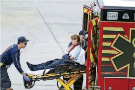  ?? [PHOTO BY DAVID
SANTIAGO/EL NUEVO HERALD VIA AP] ?? An injured woman is loaded into an emergency vehicle at Fort Lauderdale-Hollywood Internatio­nal Airport on Friday after a gunman opened fire inside a terminal of the airport, killing several people and wounding others before being taken into custody.