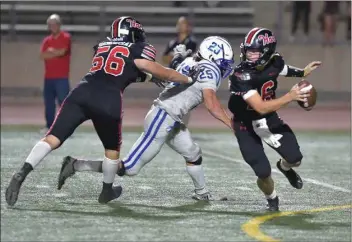  ?? Dan Watson/The Signal ?? Hart’s Jordan Sioussat (56) assists as quarterbac­k Zach Johnson (16) evades Burbank’s Lucas Sheppe (25) in the second quarter at College of the Canyons on Sept. 13. The Indians beat St. Bonaventur­e on Friday.