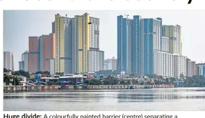  ?? — AFP ?? Huge divide: A colourfull­y painted barrier (centre) separating a waterway and a slum area, dwarfed by highrisers in Jakarta.