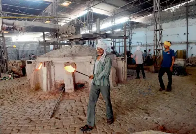  ?? AFP ?? A worker carries molten glass used to make bangles at a factory in Firozabad. —