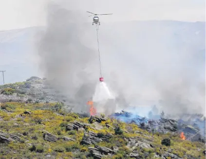  ?? PHOTO: ADAM BURNS ?? Buckets full . . . A helicopter discharges a monsoon bucket over the scrub fire.