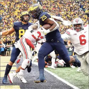  ?? Mike Mulholland / Getty Images ?? Michigan’s Hassan Haskins carries the ball into the end zone for a touchdown against Ohio State on Saturday.