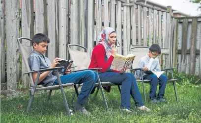  ?? COLE BURSTON FOR THE TORONTO STAR ?? Uzma Jalaluddin reads with sons Mustafa, left, and Ibrahim in 2017. She says she misses when they looked to her to schedule their days. Before their world came to a grinding halt, they were already starting to make their own plans and resisting family time.