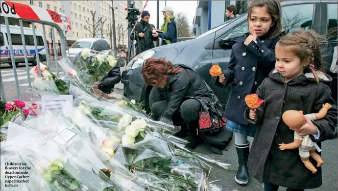  ?? PHOTO: REUTERS ?? Children lay flowers for the dead outside Hyper Cacher supermarke­t in Paris