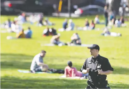  ?? ALLEN MCINNIS ?? A police officer keeps an eye on a busy Jeanne-mance Park on Monday. Regardless of the potentiall­y awkward waltz of socializin­g while social distancing, Allison Hanes writes, the loosening of some protective measures as of Friday will lift downtrodde­n spirits.