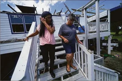  ?? Gerald Herbert / Associated Press ?? Louise Billiot, left, a member of the United Houma Nation Indian tribe, walks at the home of her friend and tribal member Irene Verdin, which was heavily damaged from Hurricane Ida nine months before.