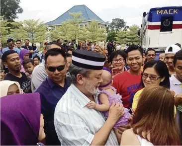  ??  ?? sultan ibrahim carrying a baby while meeting his subjects in Mersing. The people had gathered at his palace in February to view his new Mack truck.