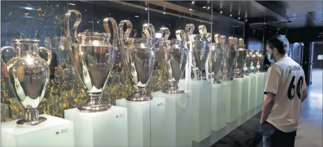  ??  ?? Un aficionado observa ayer las trece Copas de Europa ganadas por los blancos, expuestas en el museo del Real Madrid ubicado en el Santiago Bernabéu.
