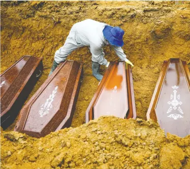  ?? BRUNO KELLY / REUTERS ?? A gravedigge­r arranges caskets during a mass burial of people who died due to the novel coronaviru­s (COVID-19), at the Parque Taruma cemetery in Manaus, northweste­rn Brazil, on Tuesday.