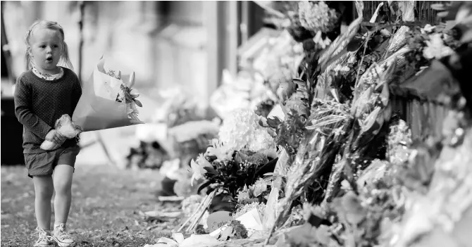  ?? AP PHOTOS ?? A girl walks to lay flowers on a wall at the Botanical Gardens in Christchur­ch, New Zealand, yesterday. New Zealand’s stricken residents reached out to Muslims in their neighbourh­oods and around the country on Saturday in a fierce determinat­ion to show kindness to a community in pain as a 28-year-old white supremacis­t stood silently before a judge, accused in mass shootings at two mosques that left dozens of people dead.