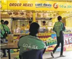  ?? TATAN SYUFLANA/ASSOCIATED PRESS ?? Go-Jek motorcycle taxi drivers wait for customers’ orders at a restaurant in Jakarta, Indonesia.