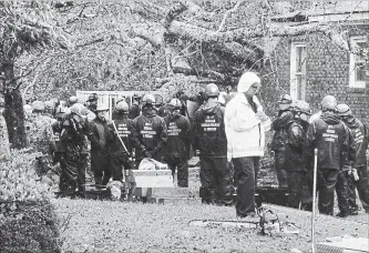  ?? CHUCK LIDDY THE ASSOCIATED PRESS ?? Rescue workers, police and fire department members wait to remove the bodies of a mother and child who were killed by a falling tree as hurricane Florence made landfall in Wilmington, N.C. Friday .