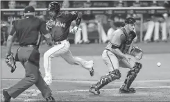  ?? Rob Foldy / The Associated Press ?? Atlanta catcher Anthony Recker (right) goes for the ball as Miami’s Adeiny Hechavarri­a crosses home plate during Saturday’s game.