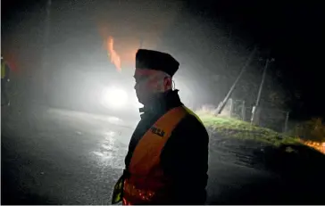  ?? GETTY IMAGES ?? A police officer walks past a check point as permitted cars are allowed to cross into the crime scene yesterday in Przewodow, Poland. Poland convened a meeting of its national security council amid reports that stray missiles hit its territory, killing two people. Russia’s defence ministry denied that its missiles hit the Nato member state.