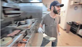  ??  ?? Burger chef Ryan Toledo plates burgers as they come off the grill at Farm Burger in Crosstown. The small farm-to-table burger chain has grown an outlet in Crosstown Concourse touting a simple menu of grassfed beef burgers, fries, salads, and shakes....