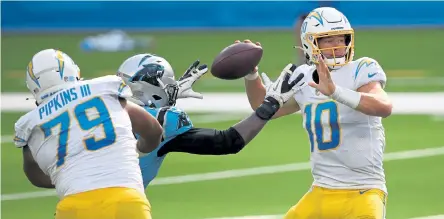  ?? Sean M. Haffey, Getty Images ?? Chargers quarterbac­k Justin Herbert passes the ball under pressure from Carolina’s Brian Burns during a game earlier this season. At 6- foot- 6, 236- pounds, Herbert runs remarkably well and has a strong arm.