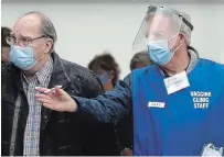  ?? CLIFFORD SKARSTEDT EXAMINER ?? Volunteer Jeff Pass assists a client at a COVID-19 vaccine clinic for people 60 years and older at the Evinrude Centre on Friday.