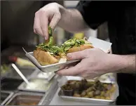  ?? NWA Democrat-Gazette/CHARLIE KAIJO ?? Cook Paul Wappler prepares a banh mi sandwich at Big Box Karaoke. The bar and restaurant mirrors Asian-style karaoke setups that feature private rooms.