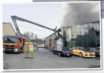  ?? Firefighte­rs were called out in force to the blaze at the car firm in Mawdesley, above; the ‘stinger’ in action directing water into the warehouse at the scene, left LANCASHIRE FIRE
SERVICE ??