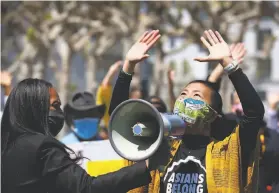  ?? Photos by Yalonda M. James / The Chronicle ?? Sasanna Yee, a yoga teacher, leads a breathing exercise as Sheryl Davis, executive director of the Human Rights Commission, holds a megaphone for her.