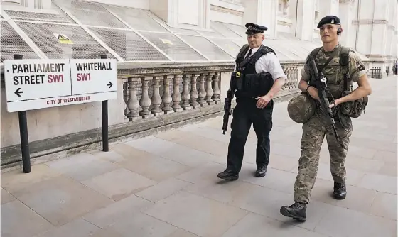  ??  ?? Um polícia e um militar em patrulha nas ruas de Londres. Soldados reforçam a segurança após o aumento do nível de alerta terrorista