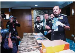  ??  ?? Major seizure: Mustafar (right) showing the seized foreign passports at the press conference in Putrajaya.