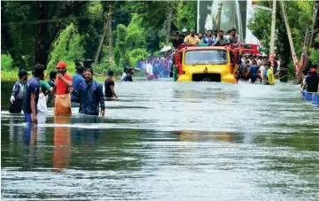  ?? Foto: dpa ?? Ein Lkw transporti­ert in Kerala Menschen auf einer überflutet­en Straße.