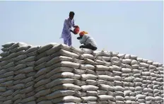  ?? Bloomberg ?? Workers drink water while stacking up wheat sacks at the grain market in Khanna district of Punjab on Sunday.