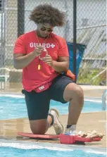  ?? ?? Lifeguard and manager Nate Smith tests water at the Riverview Parks Pool. Smith, of Lake Station, has worked at the pool for three years.