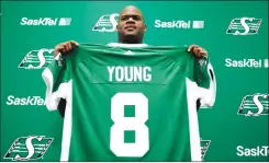  ?? Canadian Press photo ?? Vince Young, a former NFL quarterbac­k, holds up a jersey after signing with the CFL's Saskatchew­an Roughrider­s at Mosaic Stadium in Regina, Thursday.