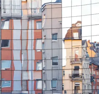  ?? FOTO: IMAGO ?? Wohnhäuser in Köln spiegeln sich in einer Glasfassad­e: Ökonomen gehen davon aus, dass deutsche Immobilien ihren Wert zu einem großen Teil behalten dürften, weil der Anstieg hier nicht so dramatisch war wie in anderen Erdteilen.