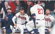  ?? AP PHOTO/JOHN BAZEMORE ?? Atlanta Braves players celebrate a two-run homer by Atlanta Braves' Austin Riley (27) on Monday in the eighth inning of Game 2 of the NL Division Series against the Philadelph­ia Phillies in Atlanta.