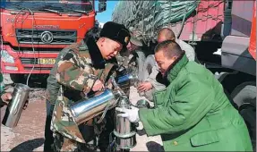  ?? LI JINWEI / FOR CHINA DAILY ?? An armed police officer serves hot water to people stranded by heavy snow on a national highway in                                                                                                                                                          ...